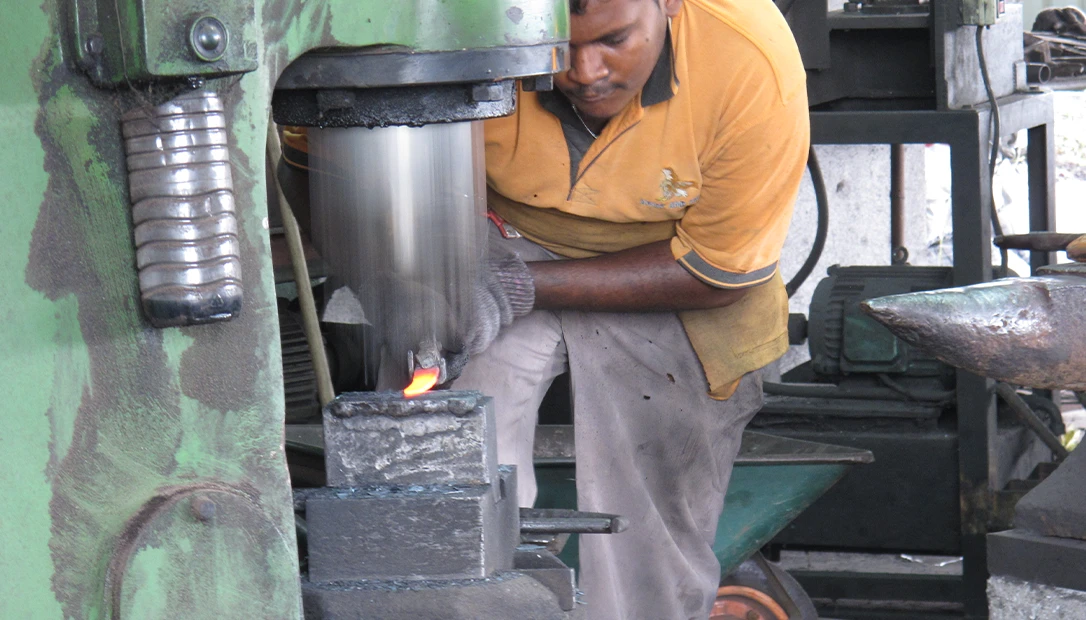 A Bidor blacksmith carefully shaping a parang blade, blending traditional skill with modern tools.